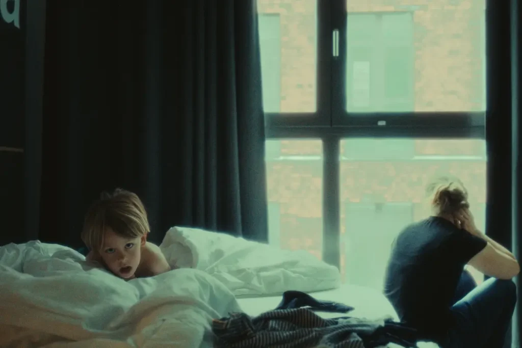 Child waking up in a hotel bed by the window