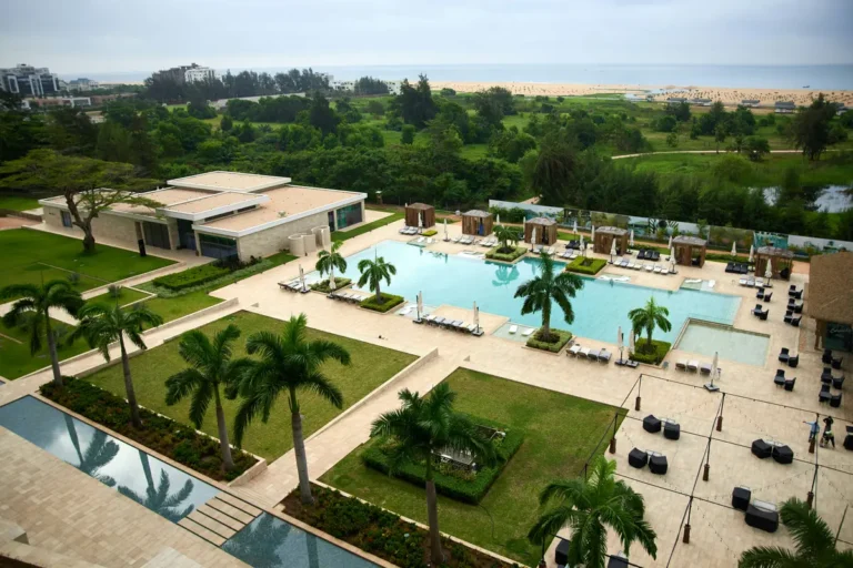 Resort with pool, palm trees, green lawns and beach