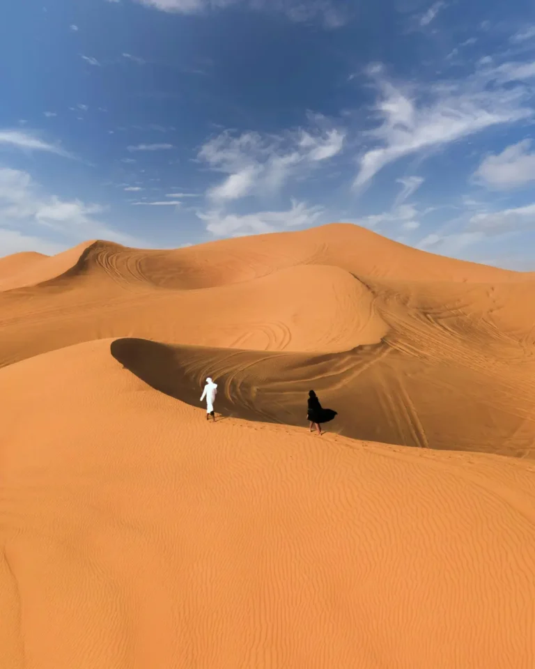 Person standing on sand dunes under a blue sky