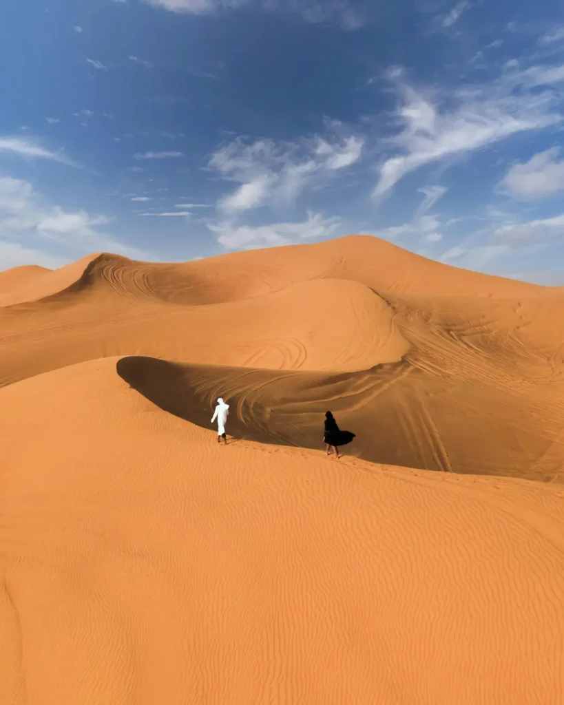 Person standing on sand dunes under a blue sky