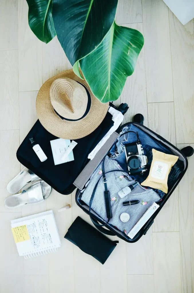 Open suitcase with travel essentials and a hat