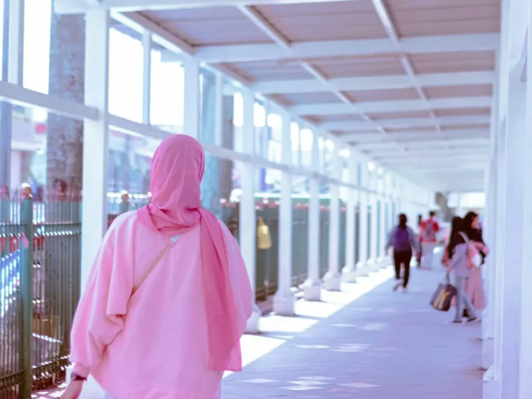 Woman in a pink hijab walking along a walkway