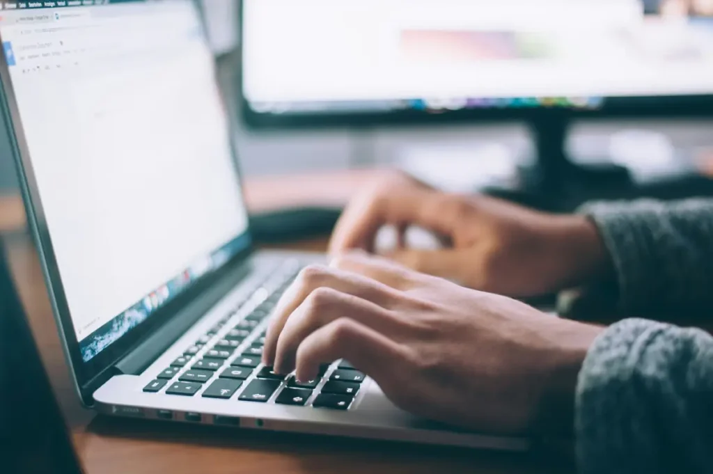 Hands typing an email on a laptop