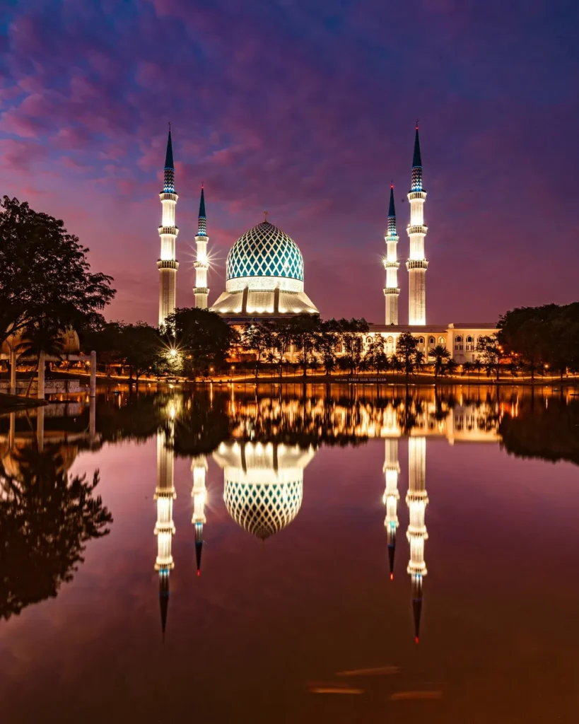 Illuminated mosque reflected in water at dusk, Malaysia